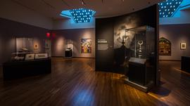 An exhibition space with artifacts displayed on shelves and images on the wall.